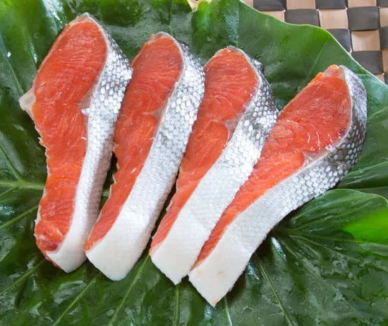 塩紅さけ（辛塩：4切れ）の商品写真。脂の乗ったおいしそうな鮭の切り身が４枚かごの上に並んでいる写真。